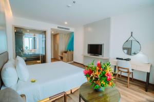 uma sala de estar com uma cama e uma mesa com flores em Mường Thanh Luxury Xuân Thành em Ha Tinh