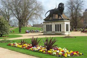 a statue of a lion in a park with flowers at Classy Central Self Contained Flat by CozyNest in Reading