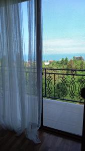 ein Fenster mit Blick auf einen Balkon mit weißen Vorhängen in der Unterkunft Iberia 2019 in Batumi