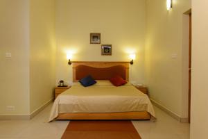 a bedroom with a bed with two pillows on it at CLUB7 HOTEL in Thiruvalla