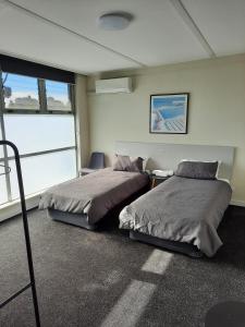DoonsideDoonside Hotel的一间卧室设有两张床、一把椅子和一个窗户。