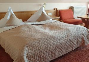 a bedroom with a large bed with a red chair at Hotel Igelstadt in Fürstenberg