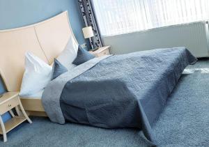 a bedroom with a large bed with blue sheets and pillows at Hotel Igelstadt in Fürstenberg