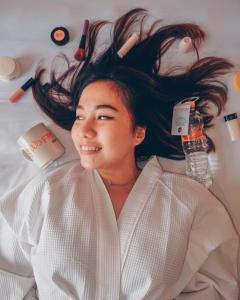 a woman laying on a bed with her hair at News Hotel Waru Sidoarjo in Waru