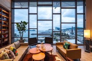 a living room with couches and tables and a large window at DarakHyu Yeosu Capsule Hotel by WALKERHILL in Yeosu