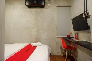 een slaapkamer met een bed en een bureau met een monitor bij RedDoorz Plus near Kawasan Sam Poo Kong Semarang in Semarang