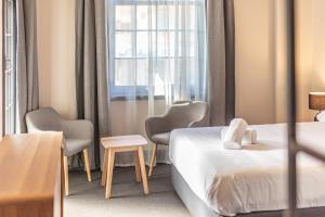 a hotel room with a bed and two chairs and a window at Lakemba Hotel in Sydney