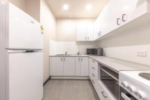 a white kitchen with white cabinets and a sink at Lakemba Hotel in Sydney