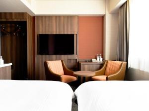 和光市にある和光市東武ホテルのベッド、椅子、テレビが備わるホテルルームです。