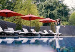 a woman walking into a swimming pool with red umbrellas at Gran Melia Jakarta in Jakarta