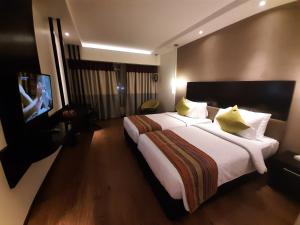 Cette chambre comprend un grand lit et une télévision à écran plat. dans l'établissement HYCINTH Hotels, à Trivandrum