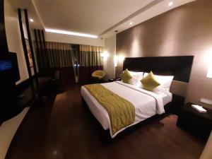 una habitación de hotel con una cama grande con almohadas amarillas en HYCINTH Hotels, en Trivandrum