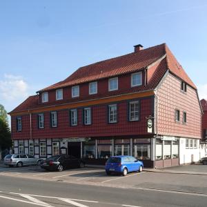 um grande edifício vermelho com carros estacionados em frente em Hotel Landhaus Greene em Einbeck