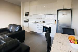 a kitchen with a table and chairs and a refrigerator at Charlestown Executive Apartments in Newcastle