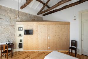 a bedroom with a large wooden closet with a tv on it at Uba - Heritage and Wine in Porto