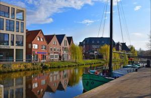 a boat is docked in a river next to buildings at LaPurka I in Nordhorn