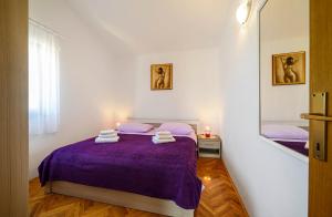 sypialnia z fioletowym łóżkiem i lustrem w obiekcie Apartments Vala w mieście Žaborić