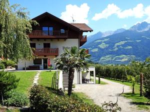 ein Haus in den Bergen mit einer Palme davor in der Unterkunft Platterhof in Dorf Tirol