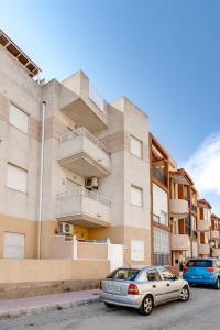 ein Gebäude mit einem davor geparkten Auto in der Unterkunft Bonito Apartamento de dos habitación y piscina in Torrevieja