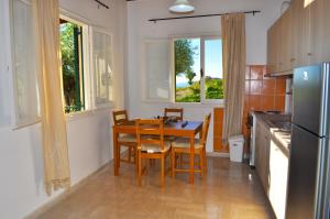 cocina con mesa, sillas y nevera en Holiday House Angelos A on Agios Gordios Beach, en Agios Gordios
