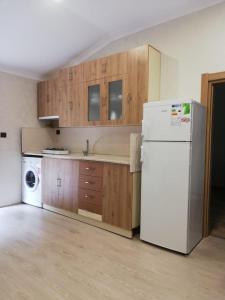 a kitchen with a white refrigerator and wooden cabinets at şerah bungawilla in Uzungöl