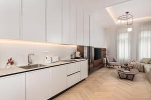 a kitchen with white cabinets and a living room at Plaza Apartments in Opatija