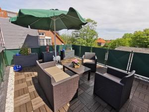 eine Terrasse mit Stühlen und einem Tisch mit einem Sonnenschirm in der Unterkunft Ferienwohnung "Kleine Nixe" in Jever