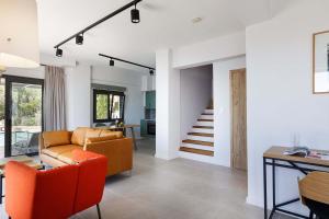 a living room with orange chairs and a couch at Anemos Luxury Villas in Rodakino