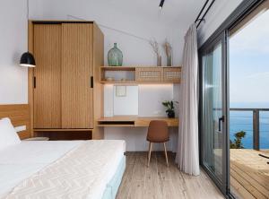 a bedroom with a bed and a desk with a window at Anemos Luxury Villas in Rodakino