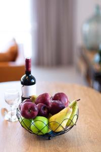 a bowl of fruit and a bottle of wine on a table at Anemos Luxury Villas in Rodakino