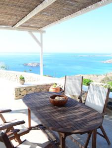 una mesa y sillas en un patio con vistas al océano en Anemolia Villa en Kárpatos