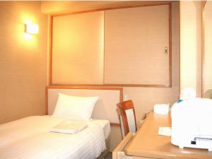 a room with a bed and a desk with a computer at Smile Hotel Hachinohe in Hachinohe