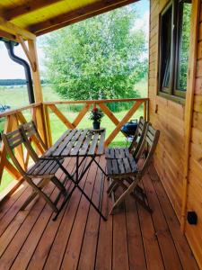 2 sillas y una mesa en el porche de una cabaña en Polne domki na Mazurach, en Stręgielek