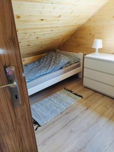 a room with a bed in a wooden attic at Polne domki na Mazurach in Stręgielek