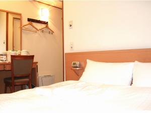 a bedroom with a bed and a desk and a chair at Smile Hotel Hachinohe in Hachinohe