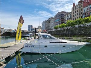 a white boat is docked at a dock at Experiencia en el mar Gijon M in Gijón