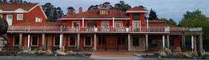 ein großes rotes Haus mit einer großen Terrasse darauf in der Unterkunft HOTEL LA CAMPANA in Llanera