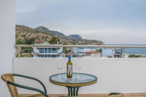 a table with two glasses and a bottle of wine at Red Hibiscus Stegna in Archangelos