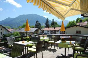 a patio with tables and chairs with mountains in the background at Hotel - Pension - Heidelberg in Ruhpolding