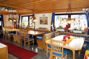 a restaurant with wooden tables and chairs and windows at Hotel - Pension - Heidelberg inkl. Chiemgaukarte in Ruhpolding