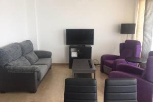 a living room with a couch and two chairs and a tv at Apartamento Angela in Villajoyosa