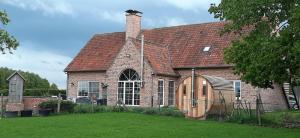 a brick house with a large window and a roof at B & B Victors Hof in Lievegem