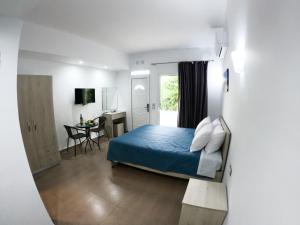 a bedroom with a blue bed and a desk at Red Hibiscus Stegna in Archangelos