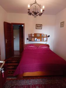 a bedroom with a red bed with a chandelier at Galambos Pincészet in Abaújszántó
