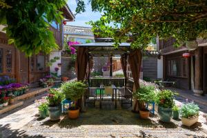 a gazebo with a table and chairs and flowers at Lijiang Gui Yuan Tian Ju Guesthouse in Lijiang
