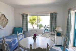 a living room with a table and chairs and a window at Prainha Lounge in Alvor