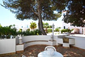 a patio with a table and chairs and a tree at Prainha Lounge in Alvor