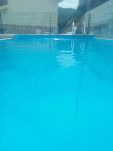 uma piscina com água azul no primeiro plano em A nossa Casa Gerês no Gerês