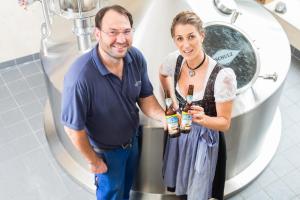 a man and a woman standing in a toilet holding bottles of beer at Brauerei und Gasthof Frischeisen in Kelheim