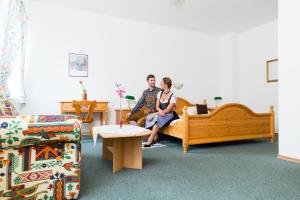 a man and woman sitting on a couch in a living room at Brauerei und Gasthof Frischeisen in Kelheim